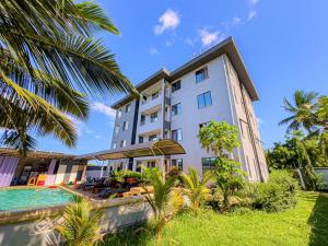 an exterior view of a building with a pool and palm trees at Diani hideouts in Kwale