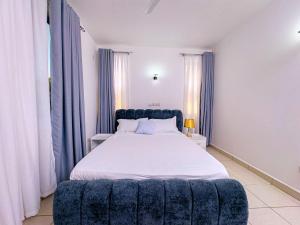 a bedroom with a large bed with a blue tufted headboard at Diani hideouts in Kwale +50 photos