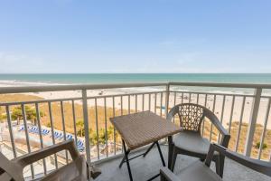 a balcony with a table and chairs and the beach at NEW Baywatch Remodled with Direct Oceanfront Views in Myrtle Beach