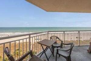 a balcony with a table and chairs and the beach at NEW Baywatch Remodled with Direct Oceanfront Views in Myrtle Beach
