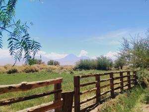 a wooden fence in a field with mountains in the background at Cabañas rústico in San Pedro de Atacama