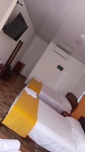 a room with a bed with a yellow blanket on it at Posada la Melosa in Guataquí