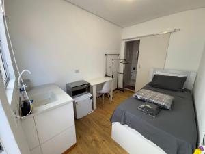 a bedroom with a bed and a desk and a sink at Pousada Solar de Mayo in Curitiba