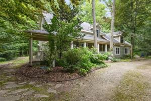 a white house with a porch in the woods at Pete's Place by Juniper Holiday + Home in Sawyer