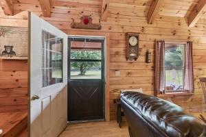 a living room with a black door and a leather couch at County Line Cabin in Woodland Beach
