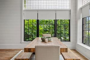 a dining room with a wooden table and chairs and windows at Black Door Bungalow by Juniper Holiday + Home in Lakeside