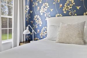 a bedroom with a white bed and a blue wall at The Birdcage by Juniper Holiday + Home in Douglas