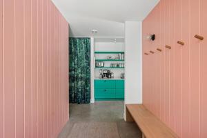 a hallway with pink and green walls and a kitchen at Owlwood by Juniper Holiday + Home in Harbert