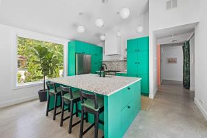 a kitchen with green cabinets and a island with stools at Owlwood by Juniper Holiday + Home in Harbert +41 photos