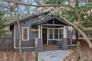 a small house with a porch with pink flowers at Meadow Pines by Juniper Holiday + Home in Michigan City