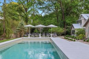 a swimming pool with chairs and umbrellas next to a house at Townie 4 - The Fern by Juniper Holiday + Home in Union Pier