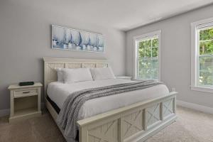 a white bedroom with a bed and two windows at Sandy Shores in South Haven