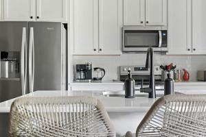a kitchen with white cabinets and a sink with two chairs at Sandy Shores in South Haven