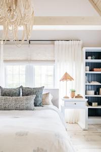 a bedroom with a white bed and a chandelier at Leo Cottage by Juniper Holiday + Home in Union Pier