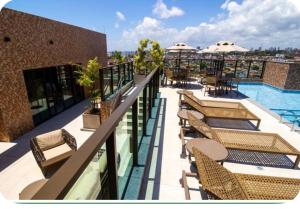 a balcony with tables and chairs and a swimming pool at Apartamento à poucos metros da praia de Pajuçara e ponta verde in Maceió