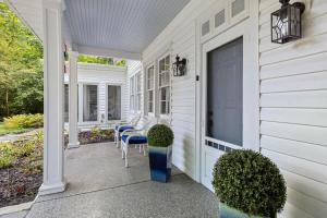 a front porch of a white house with blue chairs at Whispering Arbor by Juniper Holiday + Home in Lakeside