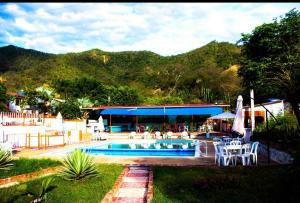 a swimming pool with tables and chairs and a building at Posada la Melosa in Guataquí