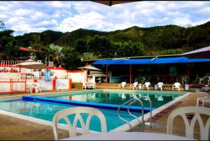 a swimming pool with chairs and tables and a building at Posada la Melosa in Guataquí +5 photos