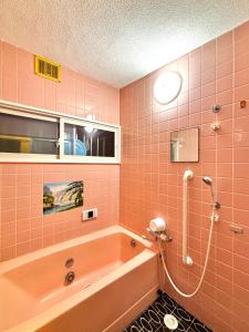a pink bathroom with a tub and a shower at 明月民宿 in Takatsuki