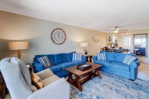 a living room with blue couches and a table at Condo in oceanfront complex with pools private beach access and balcony in Destin