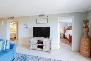 a living room with a tv and a blue couch at Condo in oceanfront complex with pools private beach access and balcony in Destin