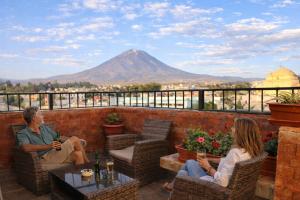 a couple sitting on a patio with a mountain in the background at Bella AQP in Arequipa