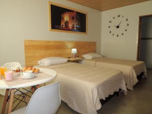 two beds in a room with a table and a clock at Jardines Inn in Trinidad