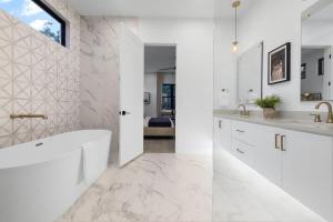 a white bathroom with a tub and a sink at Stylish Southern Home with Heated Pool in Austin
