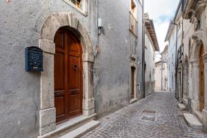 an alley with a wooden door on a building at Casa Caniglia 34 - YourPlace Abruzzo in Rivisondoli
