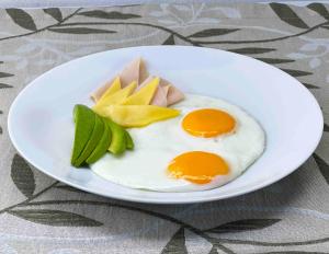 a white plate with eggs and vegetables on a table at BORÉNA Hotel Boutique in Playa del Carmen