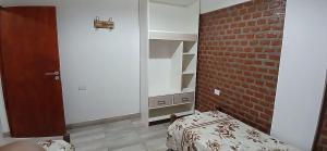 a bedroom with a mirror and a bed and a brick wall at Cabañas Termales in Termas de Río Hondo