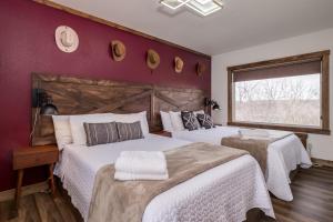 two beds in a bedroom with a red wall at Boutique Hotel King, Queen & Kitchen Suites Easy Drive to Downtown in Prescott