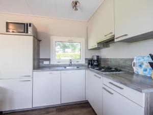a kitchen with white cabinets and a sink and a window at Sluisje 15 in Kuinre