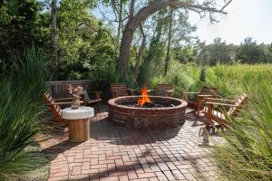 a brick patio with a fire pit and benches at Modern Coastal Home with Heated Pool in Bay Saint Louis