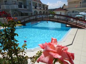 a bridge over a swimming pool with a red flower at Hotel Villa Basil in Tsilivi