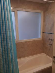 a bathroom with a bath tub and a window at Bernal Alquileres in Viedma