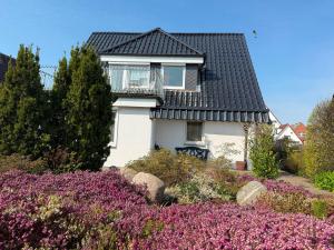 a white house with a black roof and purple flowers at Villa del Sol in Büsum