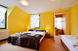 a bedroom with two beds with yellow walls and windows at Złoty Widok in Karpacz