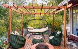 a wooden deck with chairs and a pergola at Pousada Bella Giornata in Campos do Jordão