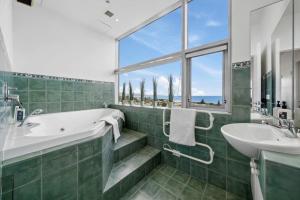 a green bathroom with a tub and a sink at U Suites at The Links in Paraparaumu +24 photos
