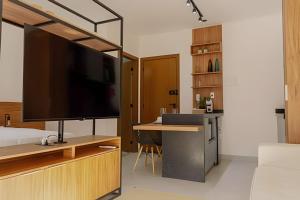a bedroom with a television and a desk with a bed at Studio Moderno com Internet e Garagem. in Três Corações