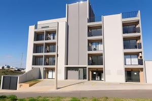 a white apartment building with a parking lot at Studio Moderno com Internet e Garagem. in Três Corações