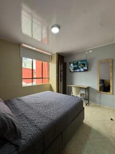 a bedroom with a bed and a table and a television at Hostelfc Movistar57 in Bogotá