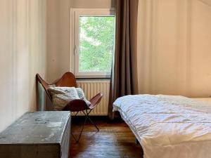 a bedroom with a chair next to a bed at Cozy Durbuy Chalet with fireplace in Dochamps