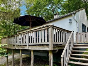 a wooden deck with an umbrella on a house at Cozy Durbuy Chalet with fireplace in Dochamps