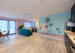 a living room with a blue couch and palm trees on the wall at Private 2 Bed Escape with Huge Parking in Ely