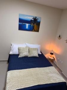 a bedroom with a bed with a blue blanket and pillows at Studio 302 Centro Imperial in Petrópolis +5 photos