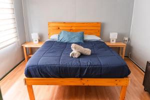 a bed with a blue comforter and a stuffed animal on it at Patagonia Sweet House in Puerto Natales