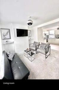 a living room with a black leather couch and tables at Medway Hidden Gem in Gillingham +10 photos