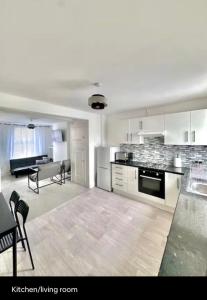 a white kitchen with a living room and a couch at Medway Hidden Gem in Gillingham